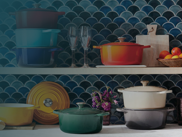 Colorful Le Creuset cookware displayed against blue tile