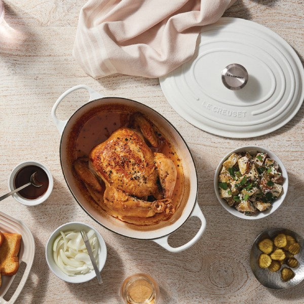 Le Creuset cookware and prepared food on a table